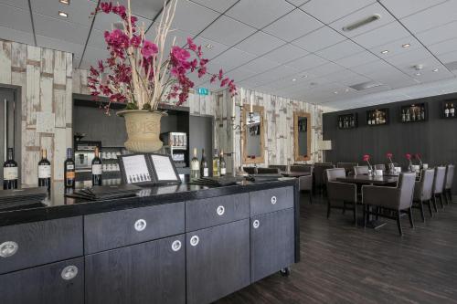 a restaurant with a bar with a vase of flowers at Fletcher Hotel Restaurant Zeeduin in Wijk aan Zee