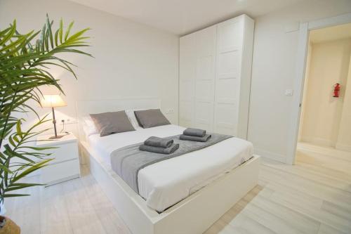 ein weißes Schlafzimmer mit einem weißen Bett und einer Pflanze in der Unterkunft Apartamento en la playa de Brazomar wifi y garaje in Brazomar