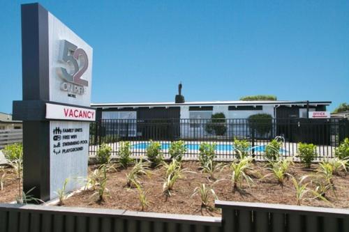 a sign in front of a building with a swimming pool at 52 on Rifle Motel in Taupo