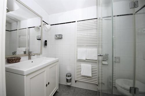 La salle de bains blanche est pourvue d'un lavabo et d'une douche. dans l'établissement Liebezeit - ehemals Hotel Dillenburg, à Dillenburg