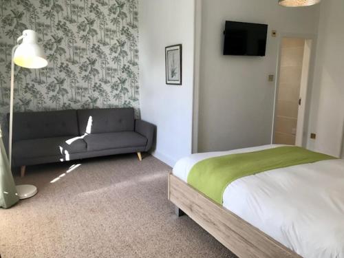 a bedroom with a bed and a couch and a television at Lunan House in Arbroath