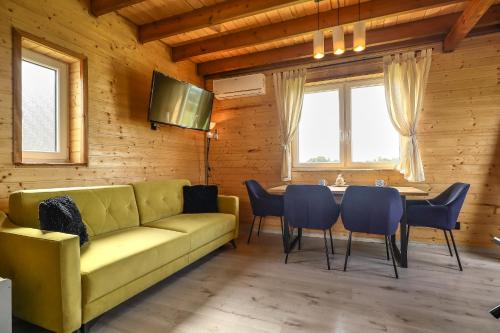 a living room with a yellow couch and a table and chairs at Jaśkowe Wzgórze domki na wynajem, balia, Szymbark DOMEK NR 1 in Szymbark