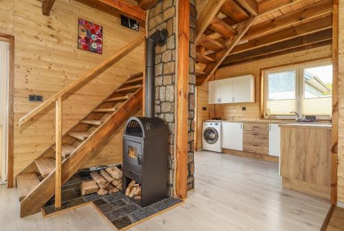 a log cabin with a wood stove in a kitchen at Jaśkowe Wzgórze domki na wynajem, balia, Szymbark DOMEK NR 1 in Szymbark