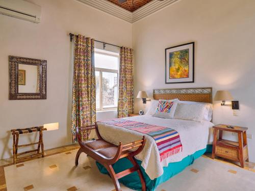 a bedroom with a bed and a chair and a window at Casona 66 Merida Boutique Hotel in Mérida