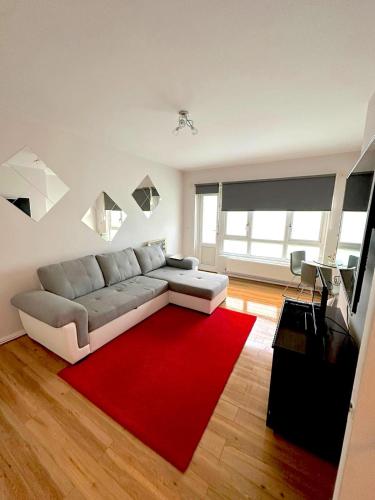 a living room with a couch and a red rug at 303 Alexandra Avenue HA2 9DX in Pinner