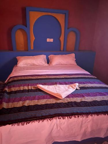 a bed with a blue headboard and two pillows on it at Riad Aicha & Camel Trekking in Merzouga