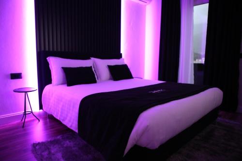 Un dormitorio con una cama con luces rosas. en Dark Boutique Hotel, en Tirana