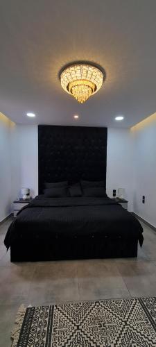 a bedroom with a black bed and a chandelier at Black in AlUla