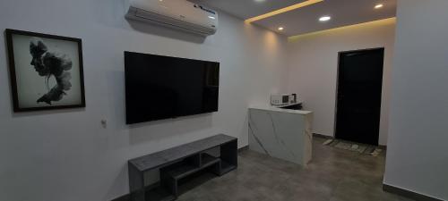 a living room with a bench and a flat screen tv at Black in Al-ʿUla
