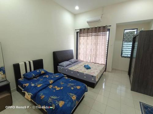 a bedroom with two beds and a window at Homestay Sofiyyah 1 in Temerloh