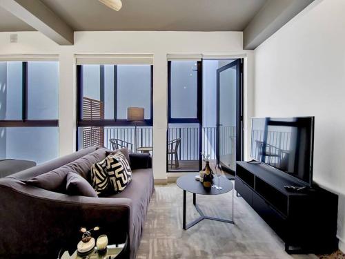 a living room with a couch and a flat screen tv at Brand new, luxury, wifi, pool with 24hr security in Cape Town