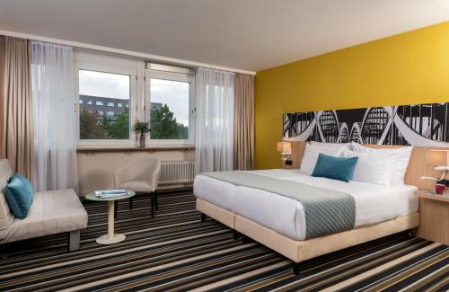 a hotel room with a bed and a chair at Leonardo Hotel Hamburg Elbbrücken in Hamburg
