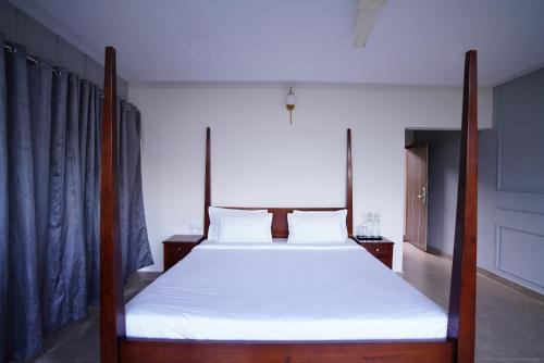 a bed with white sheets and wooden posts in a room at Ravishing Retreat Resort in Rāmanagaram