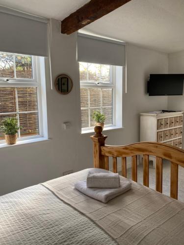 ein Schlafzimmer mit einem Bett und zwei Fenstern in der Unterkunft Little Limes an Adorable little Suffolk getaway with outside space near Woodbridge in Eyke
