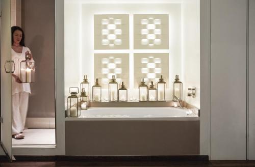 a woman standing in a bathroom with a tub filled with bottles at COMO Metropolitan London in London
