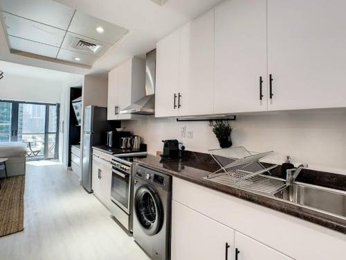 a kitchen with white cabinets and a sink and a dishwasher at Luxury Modern Studio in JLT with Amazing View & Rooftop Pool - sleeps 3 in Dubai