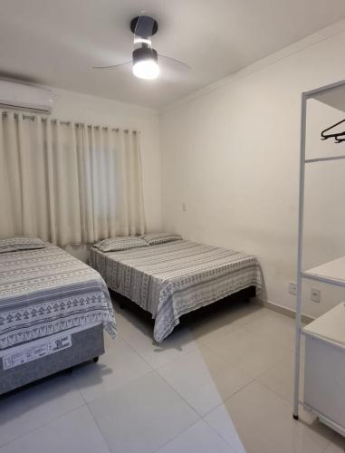 een slaapkamer met 2 bedden en een plafondventilator bij Apartamento Com Churrasqueira Maranduba Ubatuba! in Ubatuba