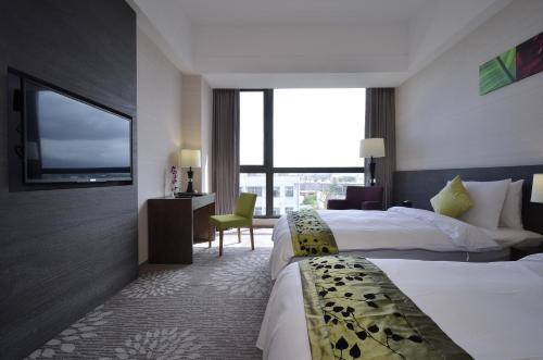 a hotel room with two beds and a flat screen tv at Hoya Hotel Taitung in Taitung City