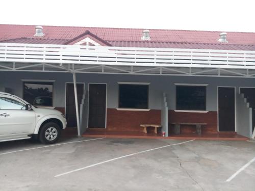 une voiture blanche garée dans un parking en face d'un bâtiment dans l'établissement Baan Din Baramee Resort, à Kamphaeng Phet
