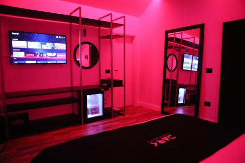 Habitación rosa con TV y espejo. en Dark Boutique Hotel, en Tirana
