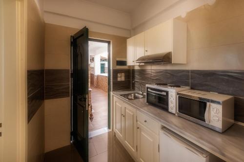 a kitchen with a stove and a microwave at Chandris Apartments in Kavos