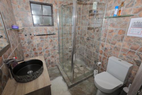 a bathroom with a shower with a toilet and a sink at Oasis in the Wild @Marloth in Marloth Park