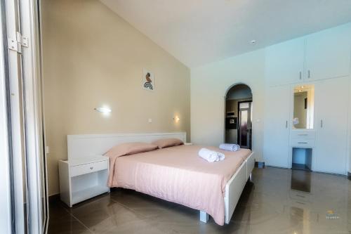 a bedroom with a bed with pink sheets and towels on it at Chandris Apartments in Kavos