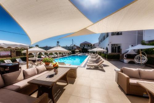 an outdoor patio with a pool and tables and chairs at Chandris Apartments in Kavos