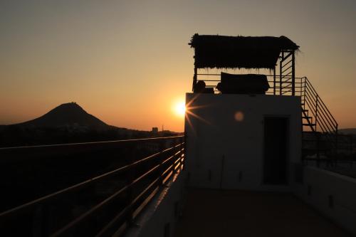 a sunset over the top of a building with a mountain in the background at The Brahma Space in Pushkar