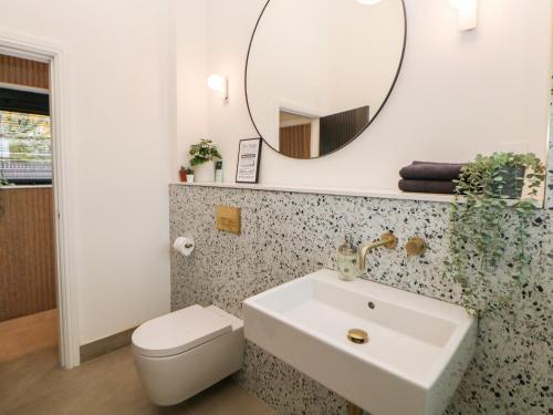 een badkamer met een witte wastafel en een spiegel bij Overlea Coach House in Birch Vale