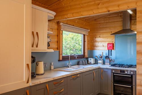 a kitchen with a sink and a stove and a window at Screel View in Kippford