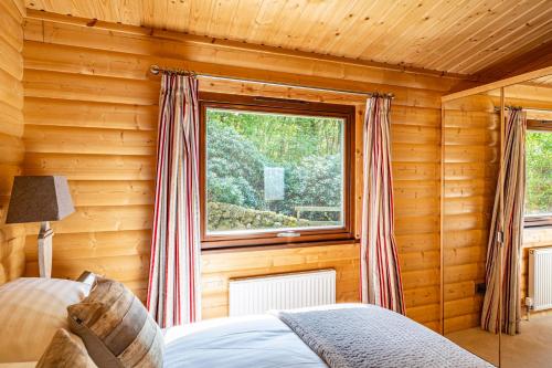 a bedroom with a window in a log cabin at Screel View in Kippford