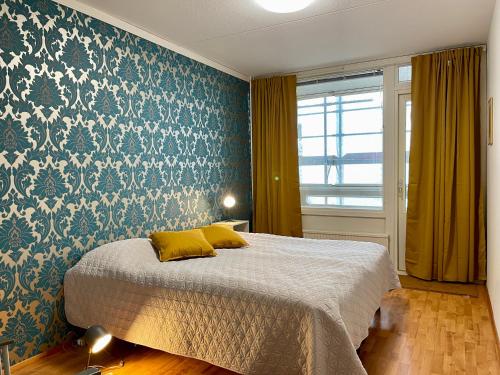 Schlafzimmer mit einem Bett mit einer blauen und weißen Tapete in der Unterkunft Porvoon Kartanonpuisto in Porvoo