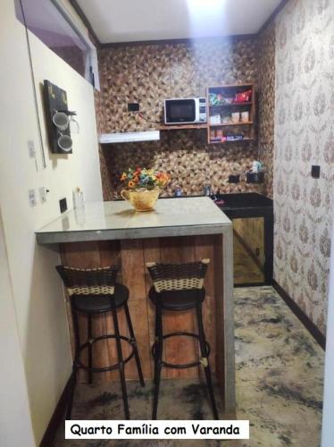 a kitchen with a counter with two bar stools at Sanctuary Pirenópolis Suítes e Flats in Pirenópolis