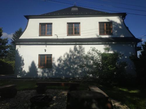 Una casa blanca con la sombra de un árbol. en Chalupa NA ZEMI 211, Andělská Hora, en Andělská Hora