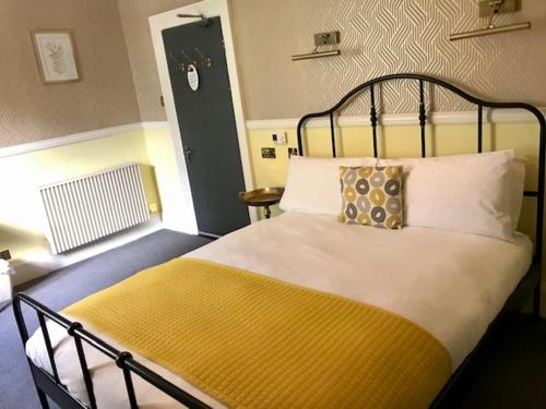 a bedroom with a large bed with a yellow blanket at Lunan House in Arbroath