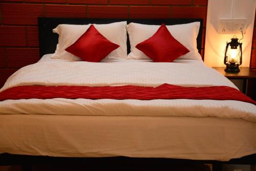 Una cama con dos almohadas rojas. en ClayNest Resorts, en Kuttālam