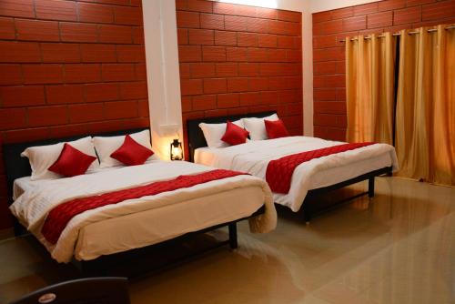 2 camas en una habitación con paredes rojas en ClayNest Resorts, en Kuttālam