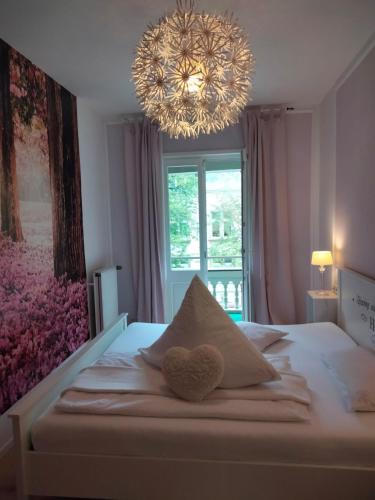 a bedroom with a bed with a heart pillow and a chandelier at Ferienwohnung Benvenuto in Bad Harzburg