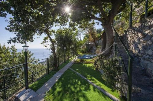 a hammock hanging from a fence next to a tree at Casa Luci relax, jacuzzi and breathtaking view in Praiano