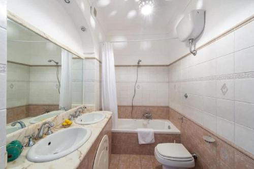 a bathroom with two sinks and a tub and a toilet at Casa Luci relax, jacuzzi and breathtaking view in Praiano