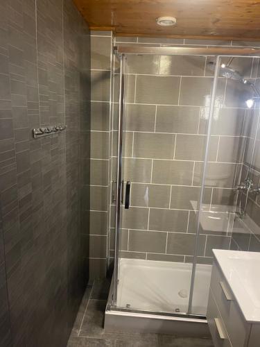 La salle de bains est pourvue d'une douche avec une porte en verre. dans l'établissement APPARTEMENT COSY AUX SAISIES n1, aux Saisies
