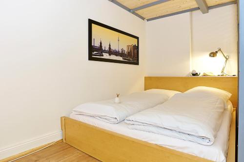 a bed with white sheets and a picture on the wall at Urban Art Kreuzberg in Berlin