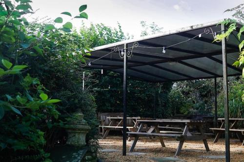 a wooden picnic table under awning with a picnic table sidx sidx at Beautiful farmhouse near Abergavenny - Sleeps 6-26 in Grosmont