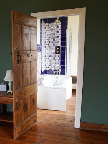 a bathroom with a tub and a window and a door at Beautiful farmhouse near Abergavenny - Sleeps 6-26 in Grosmont