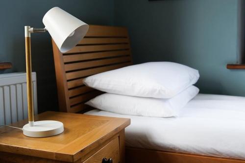 a bed with white pillows and a lamp on a table at Beautiful farmhouse near Abergavenny - Sleeps 6-26 in Grosmont
