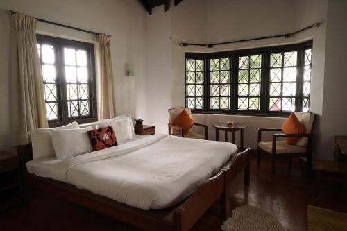 a bedroom with a large bed and two windows at Carpe DiemStay in Kushālnagar