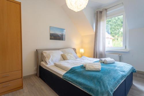 a bedroom with a bed with a blue blanket and a window at Apartament Regina in Szklarska Poręba