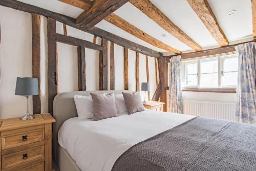 um quarto com uma cama branca e um tecto de madeira em Farriers Cottage by Bloom Stays em West Malling