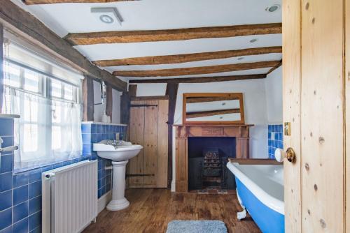 a bathroom with blue tiles and a tub and a sink at Farriers Cottage by Bloom Stays in West Malling